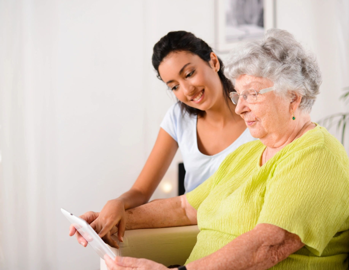 A woman and an older person looking at something on a tablet.