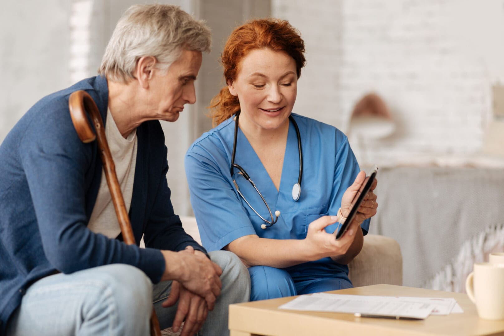 A woman in blue scrubs is looking at an ipad.