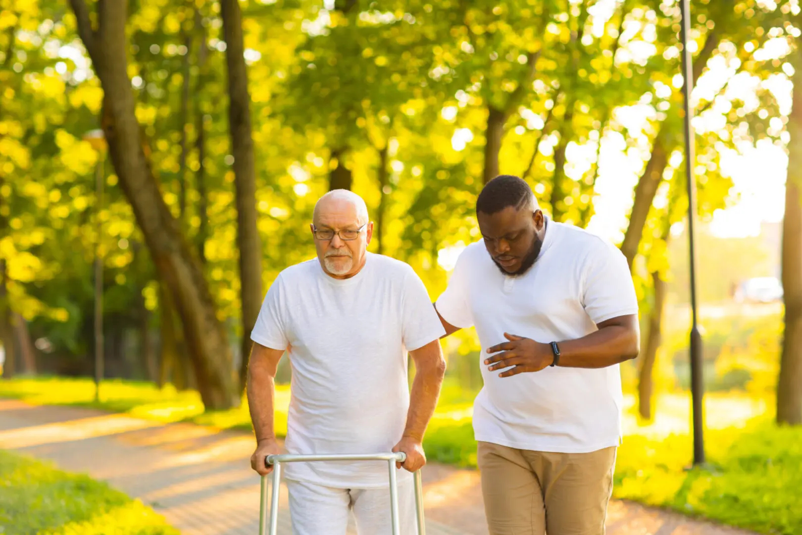 Two men walking down a path with one using a walker.